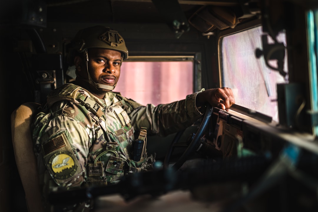 A soldier sits in a vehicle, looking at the viewer.