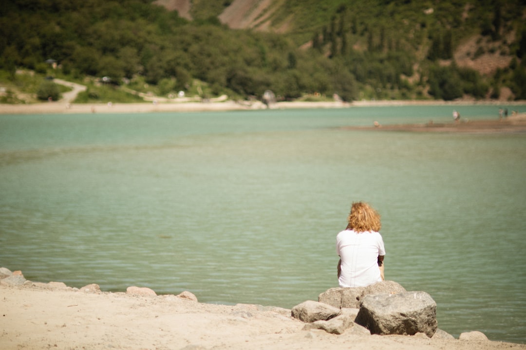 a woman sitting on a rock looking at the water